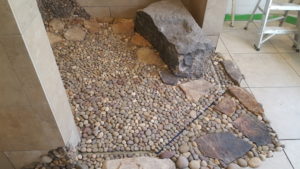 tile top linear drain with river rock and stone.